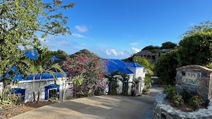 Une entrée fermée par un portail, avec une enseigne en pierre sur laquelle on peut lire « CASTAWAY », et un bâtiment surmonté d’un toit bleu.