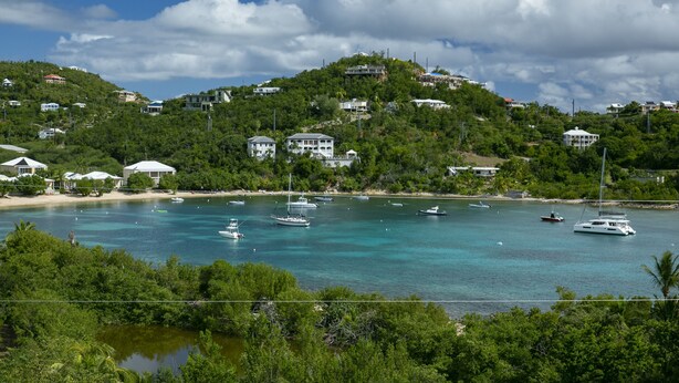Une zone côtière avec des maisons construites sur une colline, surplombant une baie turquoise où se trouvent plusieurs bateaux.