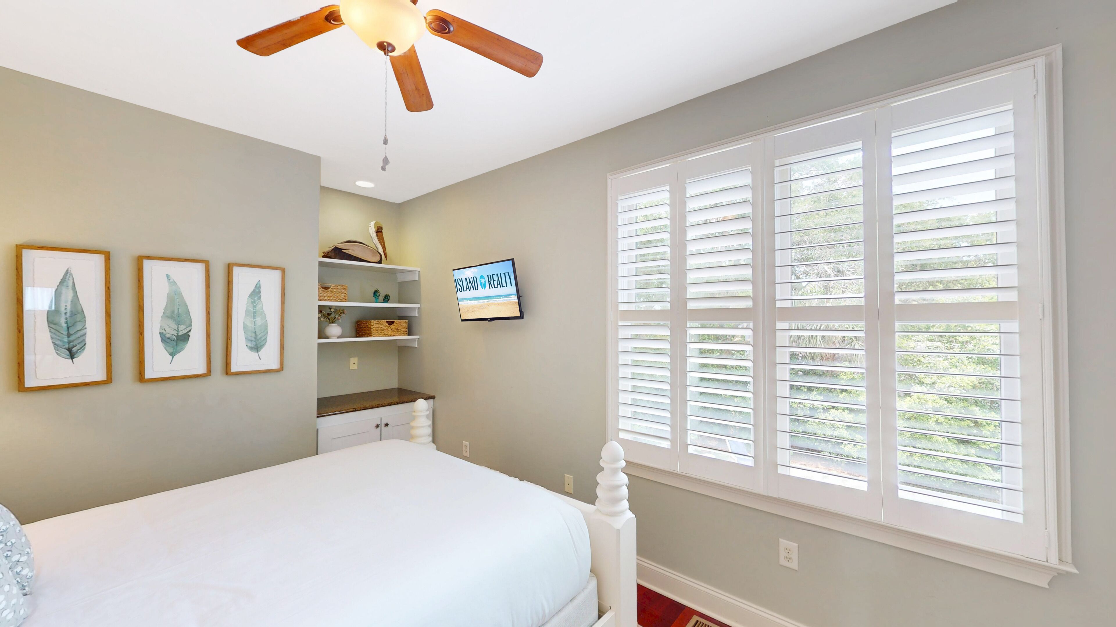 A bedroom with a bed, a ceiling fan, a TV, and a window with blinds.