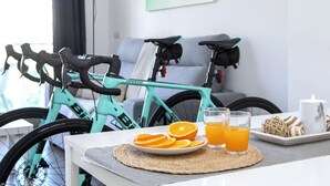 A room with a teal bicycle, a plate of orange slices, two glasses of orange juice, a candle, and a decorative item on a table. - Borumbot 8.0.3 Vista Piscina (Calpe)