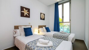 A hotel room with two beds, a window with curtains, and artwork on the walls. - Borumbot 8.0.3 Vista Piscina (Calpe)