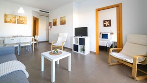 A modern living room with a dining area, a TV, and a cozy seating arrangement. - Borumbot 8.0.3 Vista Piscina (Calpe)
