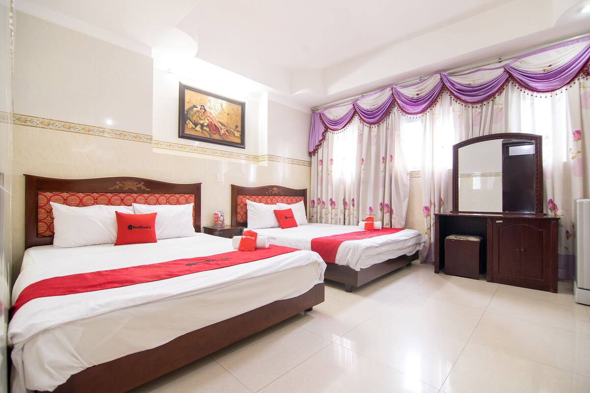 A hotel room with two beds, a large mirror, and a television.
