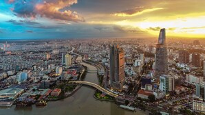 A cityscape with a prominent skyscraper, a river, and a bridge. - RedDoorz Plus near Tan Son Nhat Airport (Ho Chi Minh City)