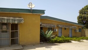 A yellow building with a satellite dish, a covered entrance, and air conditioning units. - Residence Palace Hotel (Odienne)