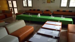 A room with multiple tables and benches, a green tablecloth, and a poster on the wall. - Residence Palace Hotel (Odienne)