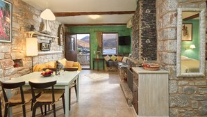 A stone-walled room with a dining table, chairs, and a sofa.