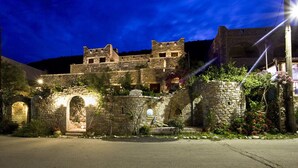A stone building with arched doorways and a staircase leading to a higher level.