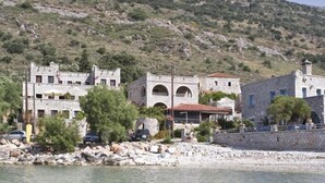 A coastal building with multiple stories, stone architecture, and a clear view of the sea.