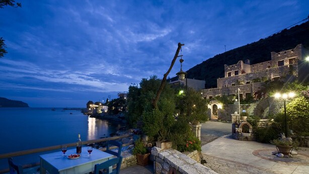 A coastal terrace with stone walls, potted plants, and a table set for dining.