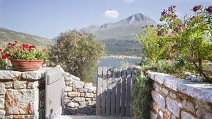 A stone pathway leading to a gate with a view of a mountain and a body of water.