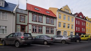Una hilera de edificios coloridos con coches aparcados al frente.