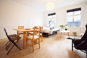 A room with a wooden dining table, chairs, a bed, a small table with a plant, and a black leather chair. - Apartment G4 (Reykjavik)