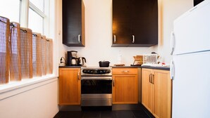 Una cocina compacta con armarios de madera oscura, un horno de acero inoxidable y un refrigerador blanco.