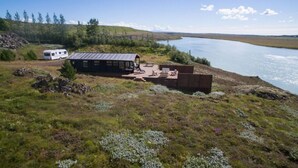 A cabin with a metal roof, a deck, and a view of a lake. - Paradise Cabin (Selfoss)
