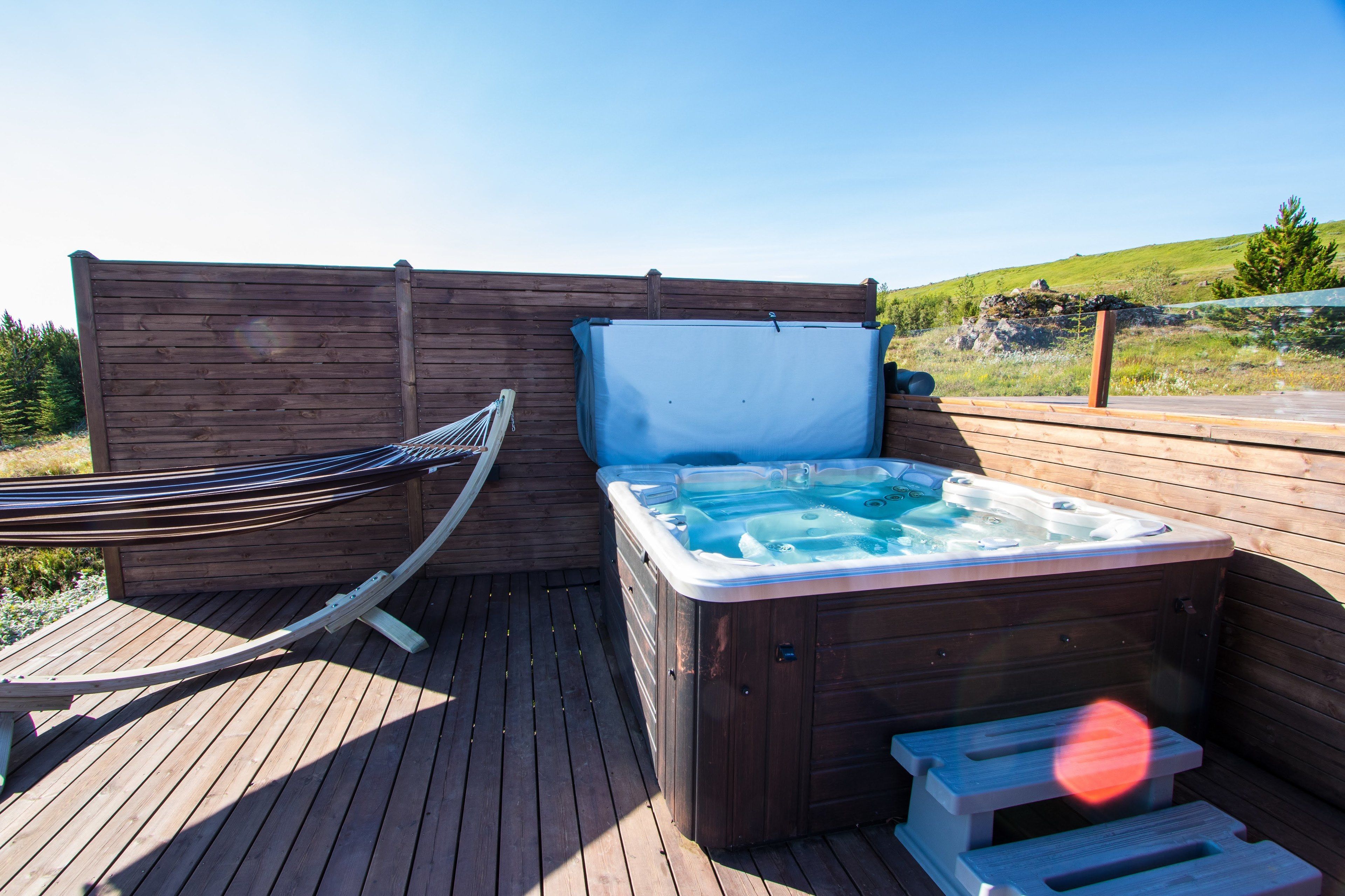 Eine Holzterrasse mit Whirlpool und Hängematte.