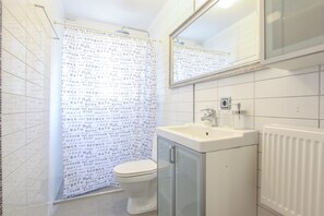 A bathroom with a toilet, sink, and mirror. The walls have a pattern of words. - Apartment R47 (Reykjavik)