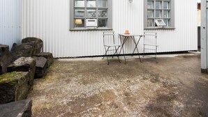 A building with two windows, a small table with chairs, and a concrete floor. - Apartment SK2 (Reykjavik)