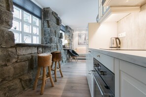 A kitchen with stone walls, wooden stools, and modern appliances. - Apartment SK2 (Reykjavik)