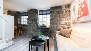A modern living room with a stone wall, a sofa, a coffee table, and a bookshelf. - Apartment SK2 (Reykjavik)