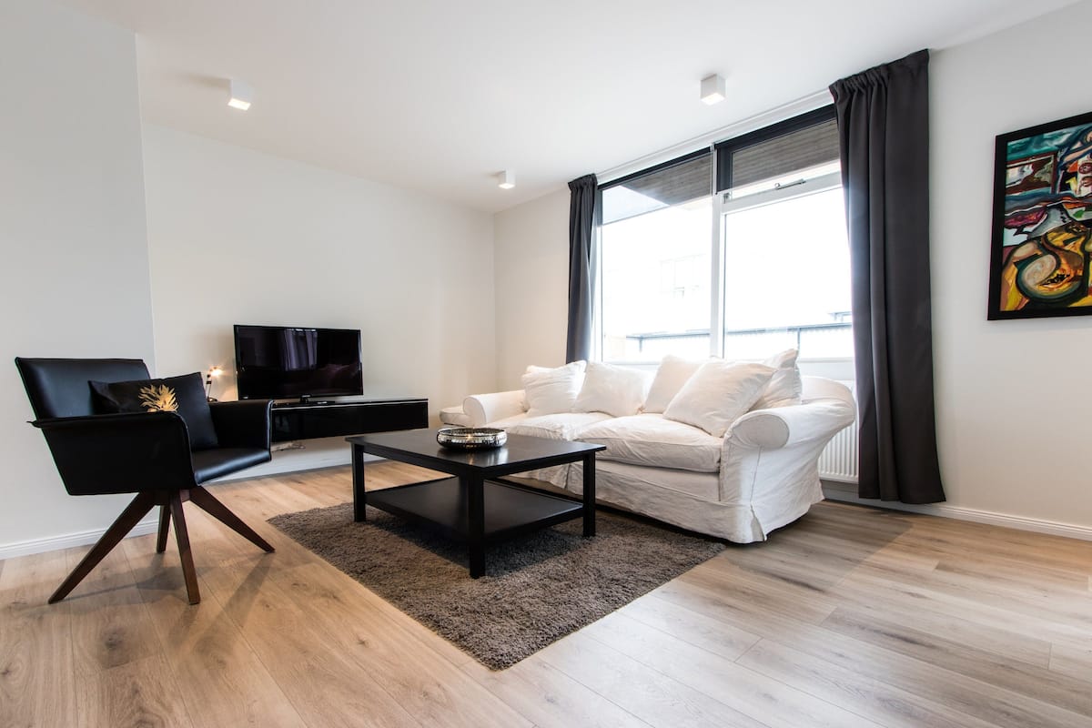 A modern living room with a white sofa, black armchair, and a black coffee table.
