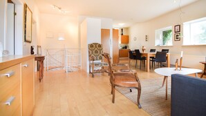 A spacious living area with a dining table, chairs, a sofa, and a kitchen area with wooden cabinets and a countertop. - Apartment Þ6 (Reykjavik)