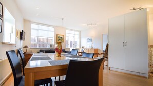A spacious dining area with a wooden table and black chairs, large windows, and a white wardrobe. - Apartment Þ6 (Reykjavik)