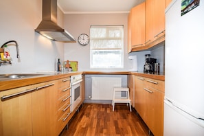Kitchen features an oven, stainless steel sink, and wooden cabinets with silver handles.