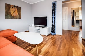 Relax in this stylish living room with a flat-screen TV, abstract art, and a comfortable sofa.
