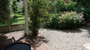 A garden with a wooden deck, gravel path, and flowering bushes. - Chez Babeth (Toulouse)