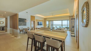 A spacious living area with a large dining table, comfortable seating, a TV, and a view of the outdoors. - Barceló Maya Riviera - Adults Only - All Inclusive (Xpu-Ha)