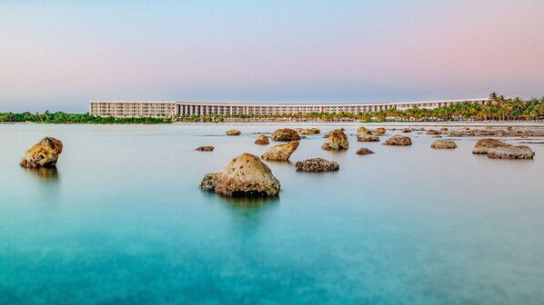 A coastal hotel with a beachfront view, featuring large rocks in the water and a long building with multiple balconies. - Barceló Maya Riviera - Adults Only - All Inclusive (Xpu-Ha)