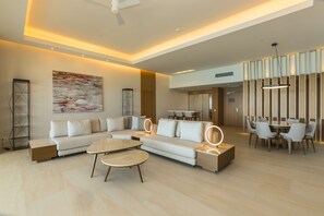 A modern living room with a sectional sofa, a round coffee table, and a dining area with a table and chairs.
