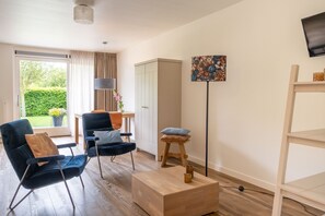 A modern living room with a sofa, a chair, a small stool, a cabinet, and a floor lamp. - Peace, space and comfort in ParelDuyn, situated between the village of Oostkapelle and the beach. (Oostkapelle)