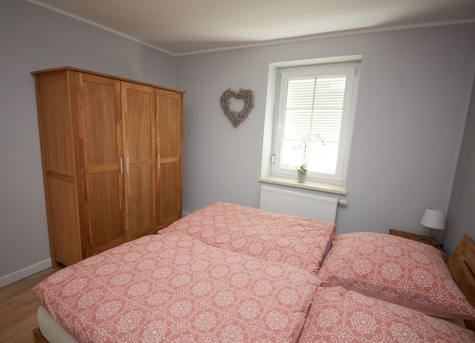 Un dormitorio con cama, armario, ventana con persianas y un adorno en la pared.