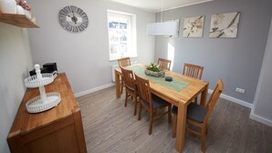 A dining area with a wooden table and chairs, a decorative clock, and artwork on the walls. - Holiday home Eifelträume for 6 people (Birresborn)