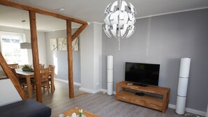 A modern living room with a wooden TV stand, a flat-screen TV, and a unique spherical chandelier. - Holiday home Eifelträume for 6 people (Birresborn)