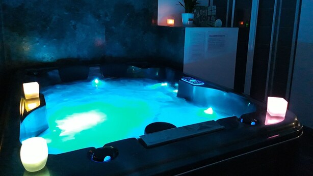 Un jacuzzi con luces brillantes, una planta en maceta y un cartel en la pared.