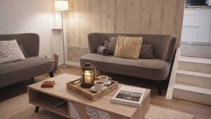 Un salón acogedor con una mesita de madera, un farol, dos tazas de café y un libro titulado 'City at Dusk'.