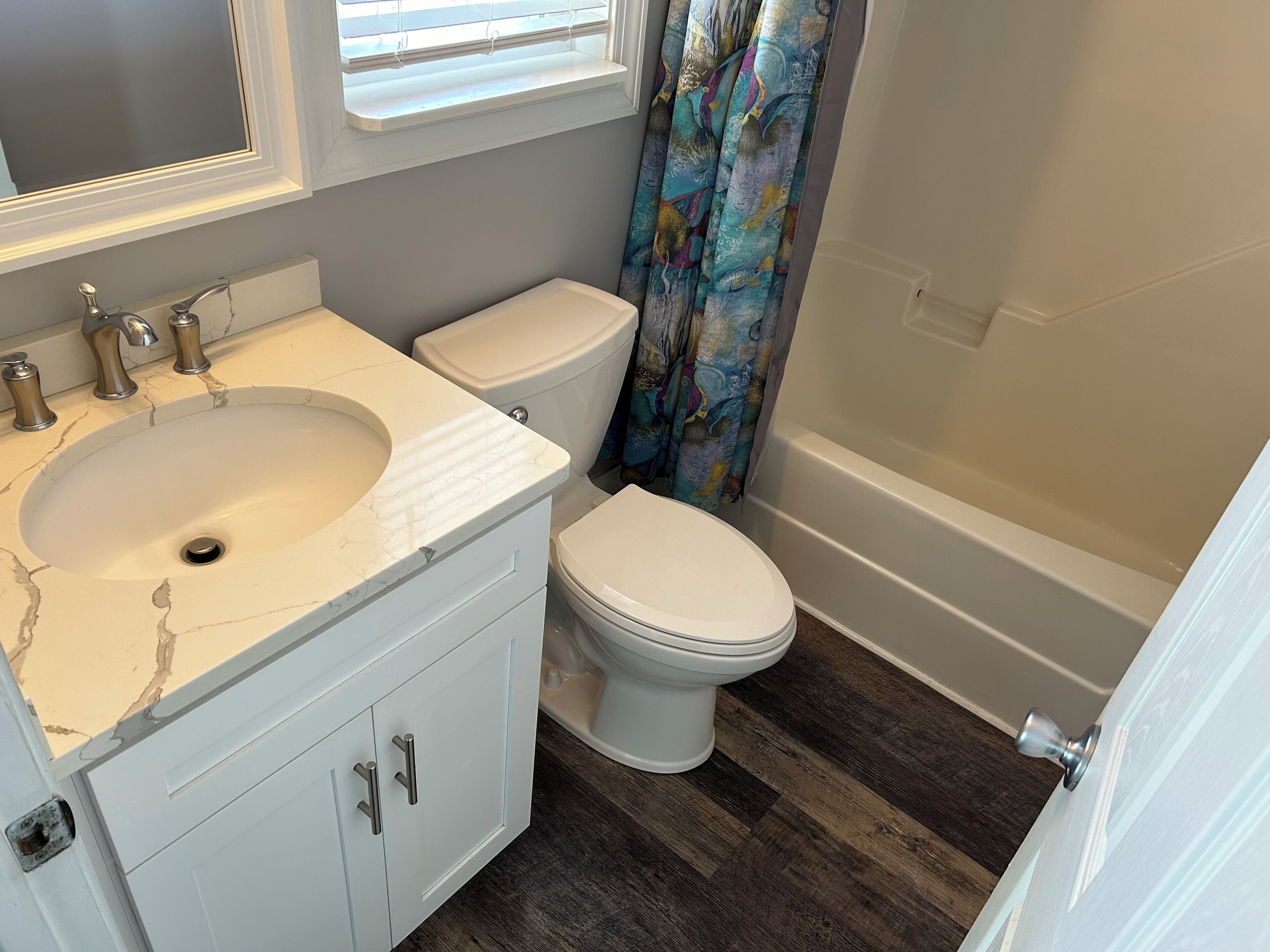 Une salle de bain avec un lavabo blanc, un meuble-lavabo, des toilettes et une baignoire.