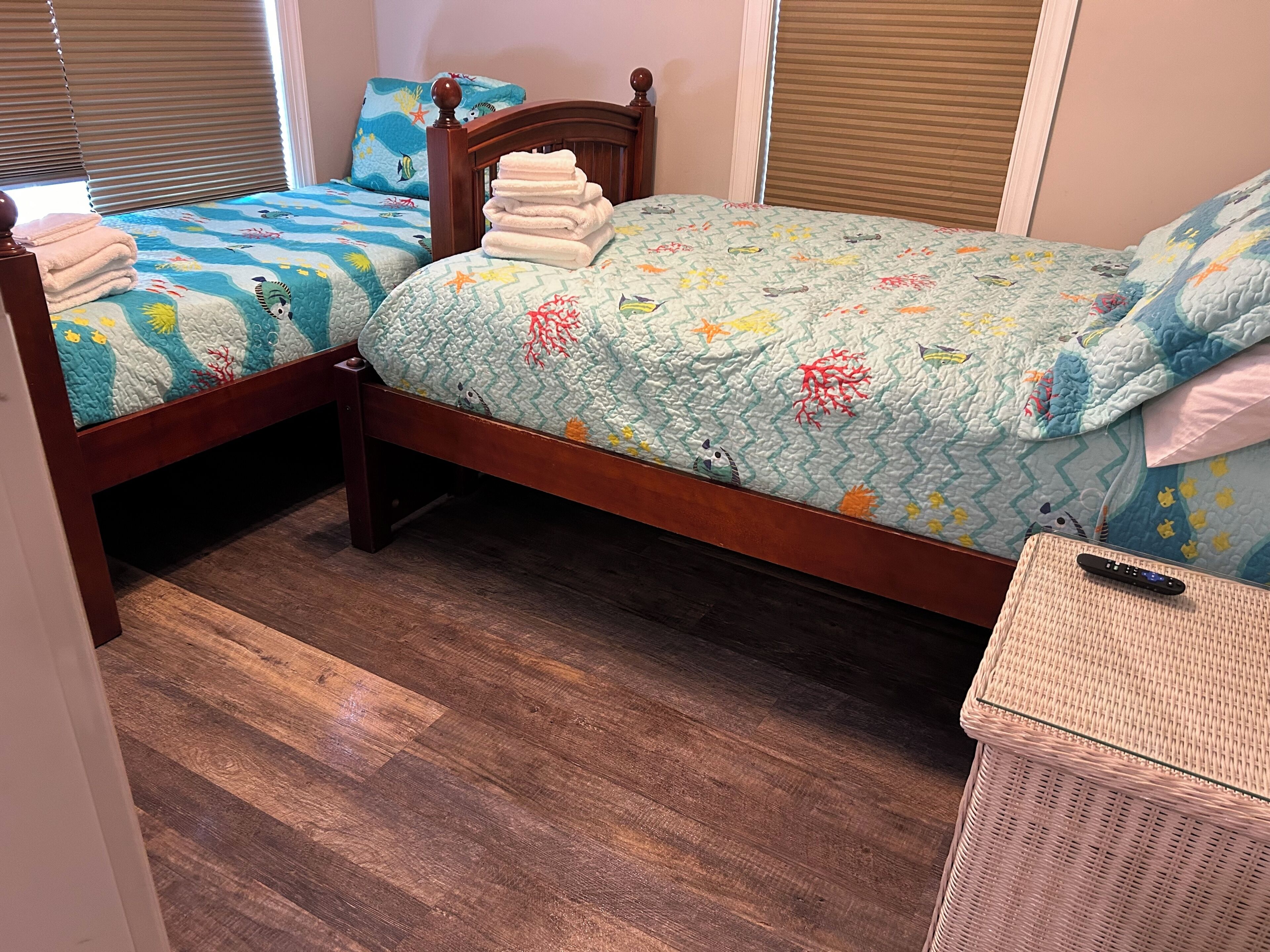 A bedroom with two wooden beds, each with a blue and white quilt featuring marine life.