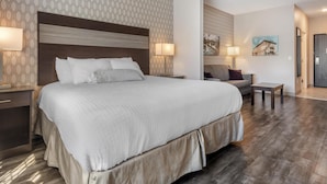 A hotel room with a large bed, two bedside tables, a small table, and a chair. - Best Western Plus Saint Peter (Saint Peter)