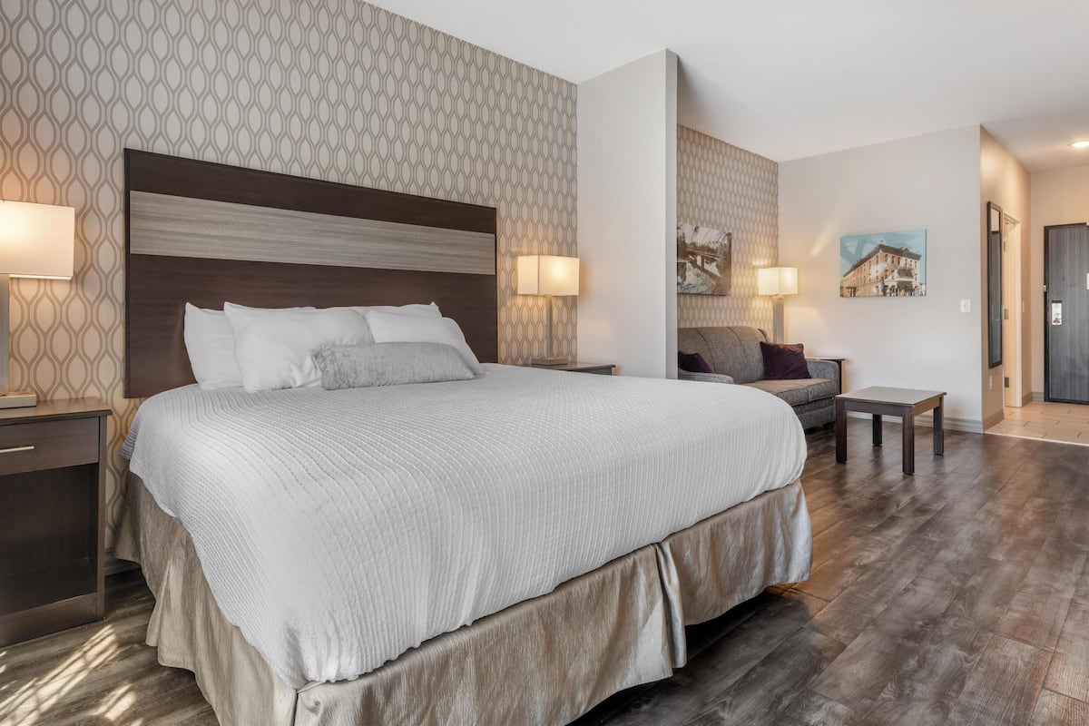 A hotel room with a large bed, two bedside tables, a small table, and a chair.