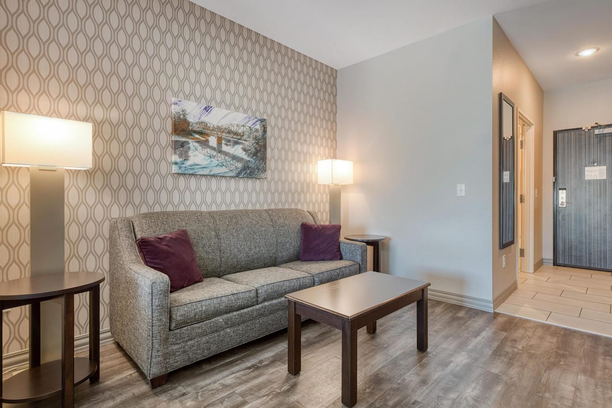 A modern living room with a patterned wallpaper, a sofa with two cushions, a coffee table, and two floor lamps.