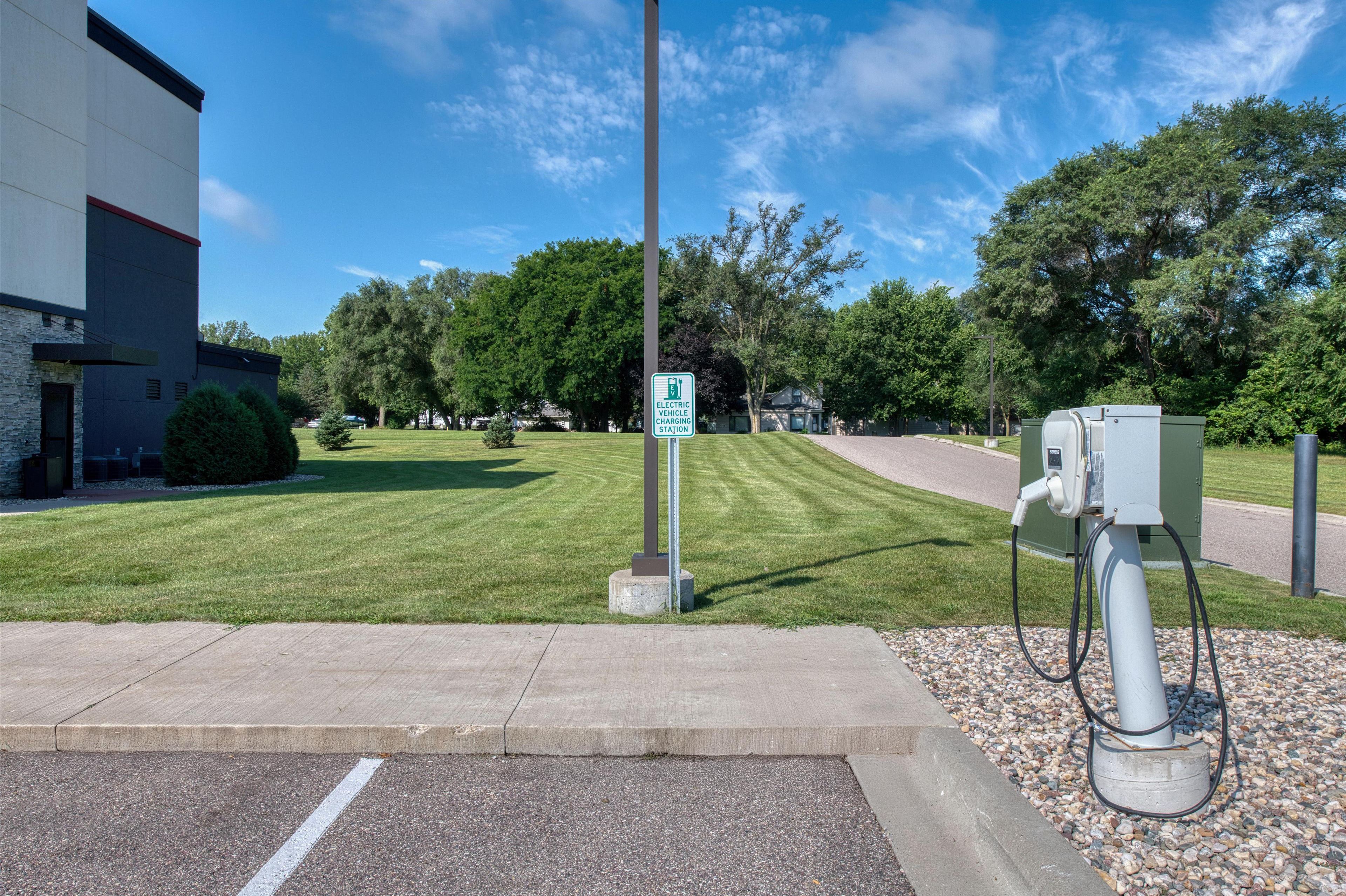 An electric vehicle charging station in a parking lot with a building in the background.