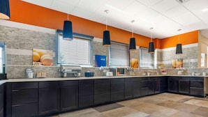A modern kitchen with dark cabinets, a large island, and a tiled backsplash. - Comfort Inn Portales (Portales)