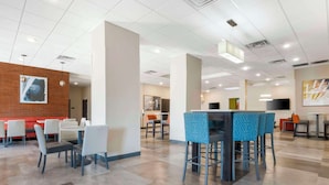 A spacious indoor area with multiple seating arrangements, including tables and chairs, and a large pillar in the center. - Comfort Inn Portales (Portales)