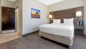 A hotel room with a large bed, two bedside lamps, a nightstand, a wooden headboard, and a painting of a desert landscape. - Comfort Inn Portales (Portales)