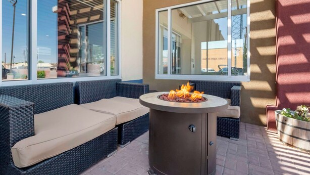 A patio area with a round fire pit, outdoor seating, and a view of a public library. - Comfort Inn Portales (Portales)