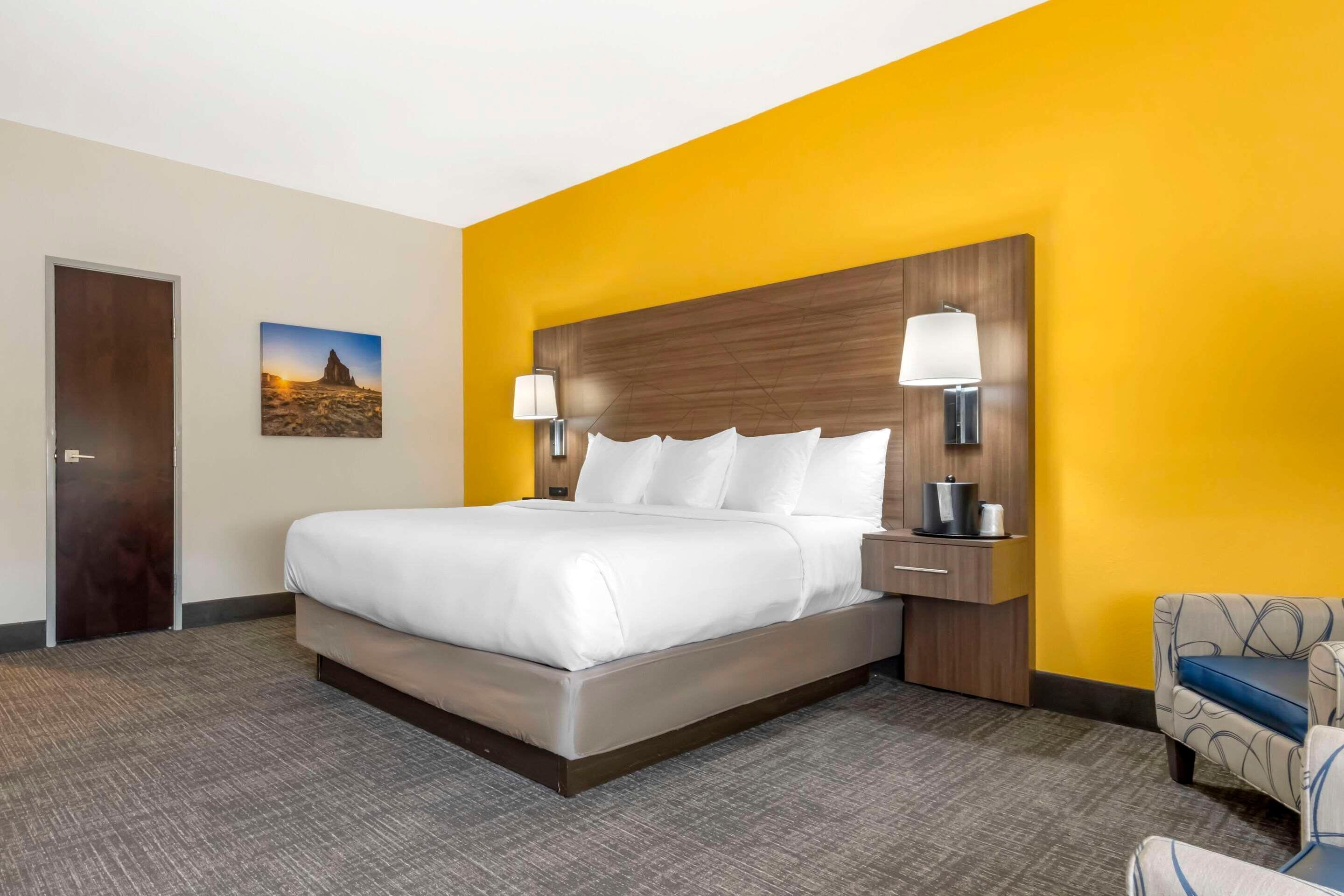 A hotel room with a large bed, bedside lamps, a nightstand, and a chair.
